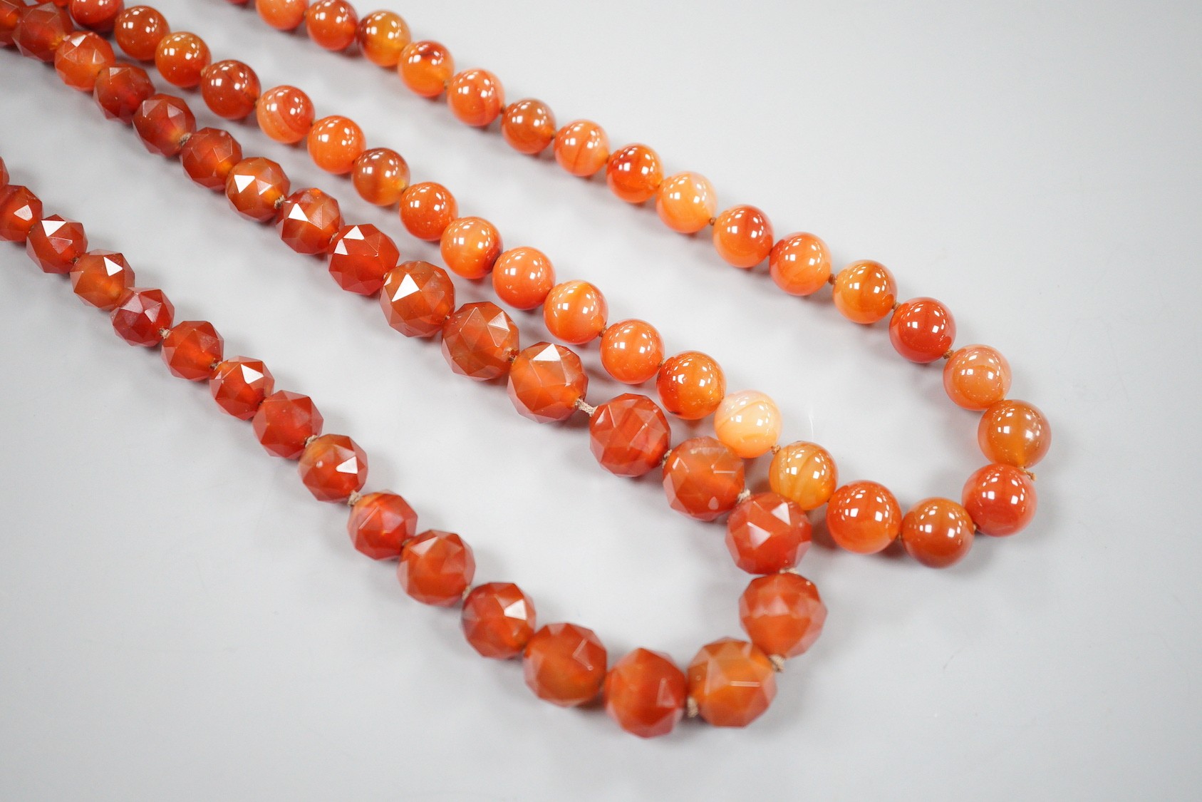 Two single strand carnelian necklace, one with facet cut beads, 44cm & 60cm, both with yellow metal clasps.